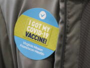 A person wears a sticker after they were given the first of two doses of the Pfizer vaccine for COVID-19, Sunday, Jan. 24, 2021, at a one-day vaccination clinic set up in an Amazon.com facility in Seattle and administered Virginia Mason Franciscan Health. (AP Photo/Ted S.