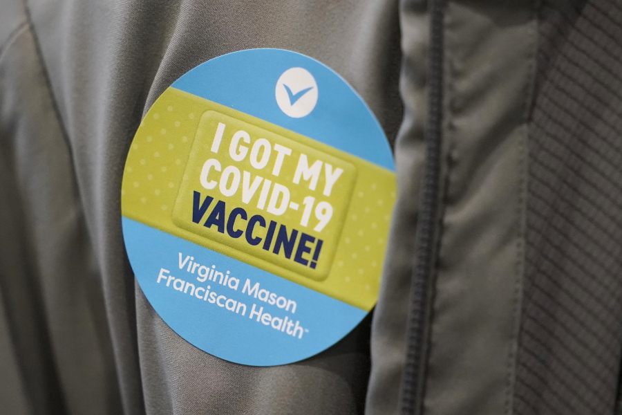 A person wears a sticker after they were given the first of two doses of the Pfizer vaccine for COVID-19, Sunday, Jan. 24, 2021, at a one-day vaccination clinic set up in an Amazon.com facility in Seattle and administered Virginia Mason Franciscan Health. (AP Photo/Ted S.