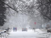 Two people hold hands while walking south on Madison Street toward 27th Avenue in Bellevue, Neb., during a winter storm warning on Monday, Jan. 25, 2021.