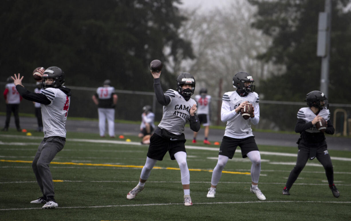 Camas quarterbacks, including Nathan Criddle, left center, and Jake Blair, right center, throw during a drill on Monday at Camas High School. Official practices began across Clark County on Monday as the return of high school sports nears.