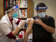 A CVS staff member administers the Pfizer COVID-19 vaccine Dec. 21 at Rose Villa Senior Living in Oak Grove, Ore., just outside of Portland.