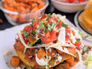 These vegetarian tostadas are stacked with two layers of smashed pinto beans, lettuce, pico and roasted sweet potatoes and bell peppers. Crumbled queso fresco and lime crema add the crowning touch.