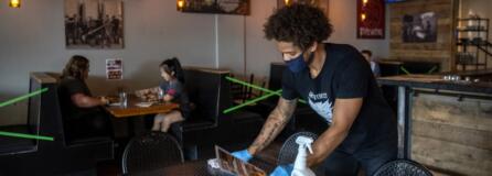 Bartender Britton Brown disinfects a table after customers leave Heathen Brewing in Vancouver in July.