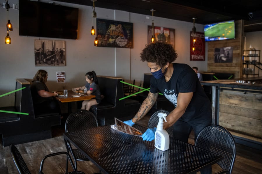 Bartender Britton Brown disinfects a table after customers leave Heathen Brewing in Vancouver in July.