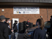 Automotive instructor Adam Eldridge, center in red mask, works with students as they prepare to push a car inside the auto shop at Cascadia Tech Academy. Remote learning has been a challenge for students learning hands-on occupations.