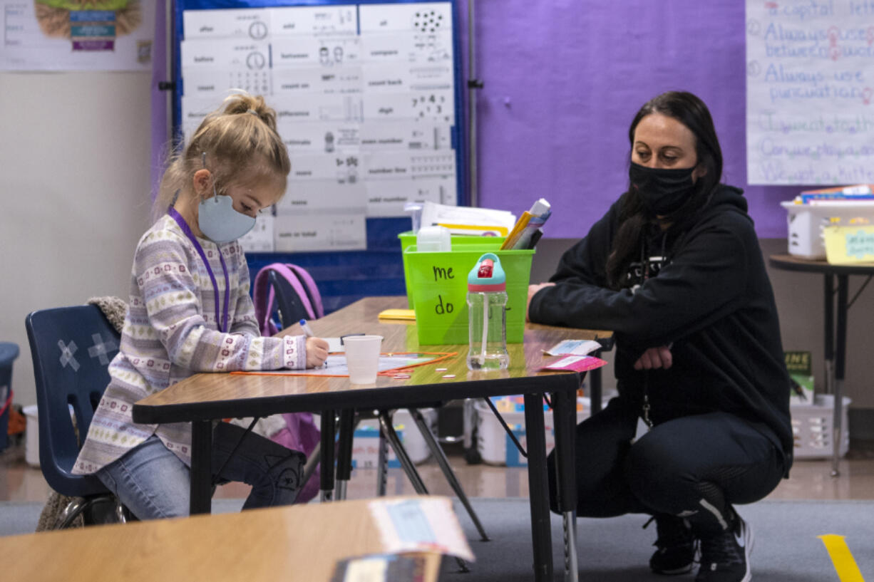 Kindergartner Knightley Wells does a math assignment while educational assistant Tiffany Shimmin observes last month at Captain Strong Primary School in Battle Ground.