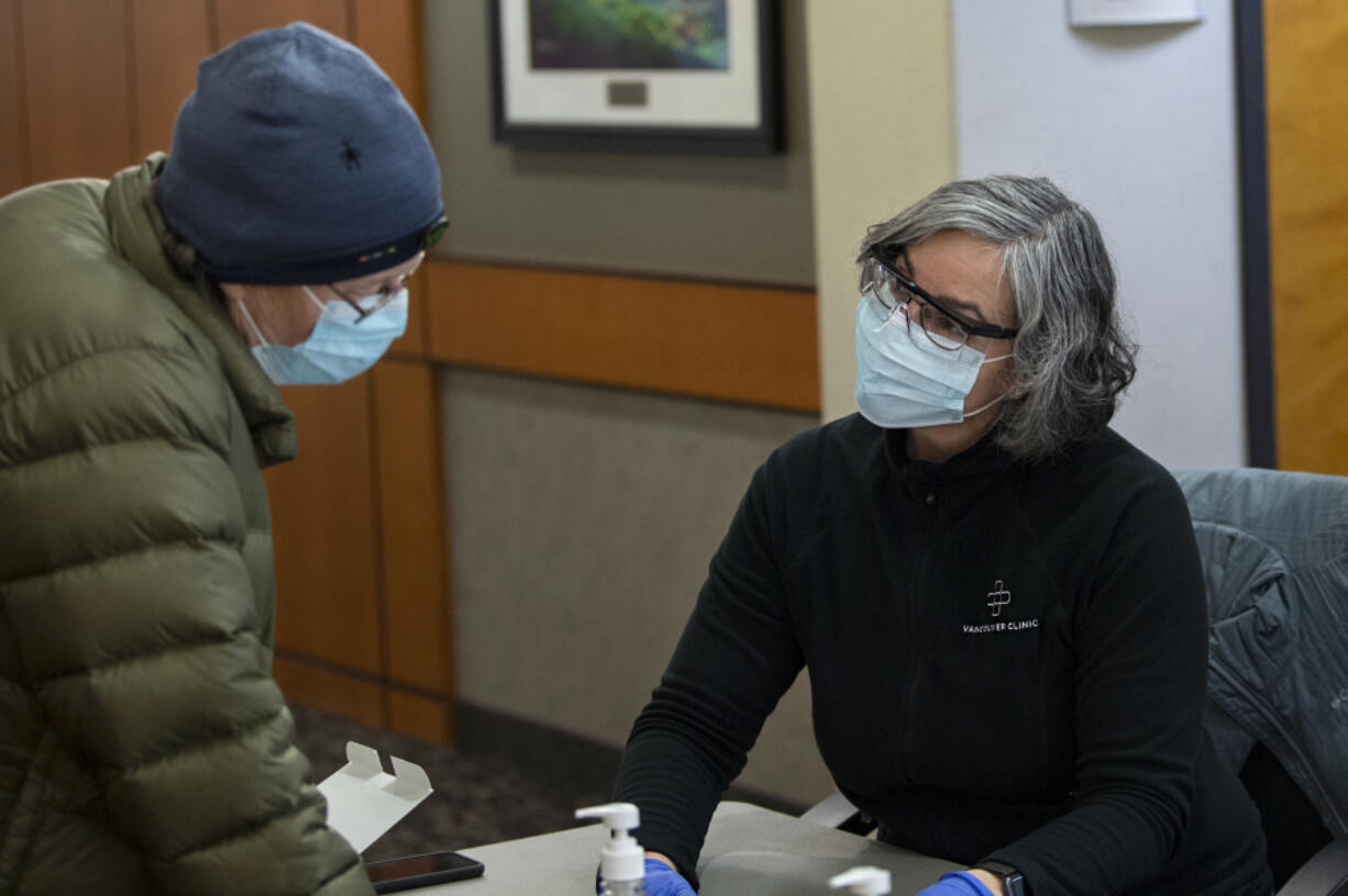 Elizabeth Rantz answers screening questions from Dr. Keren Rosenblum before receiving the COVID-19 vaccine at the Vancouver Clinic on 87th Avenue in Vancouver. Rosenblum, an OB-GYN who is vaccinated, said she now has less anxiety when she comes home to her family after work.