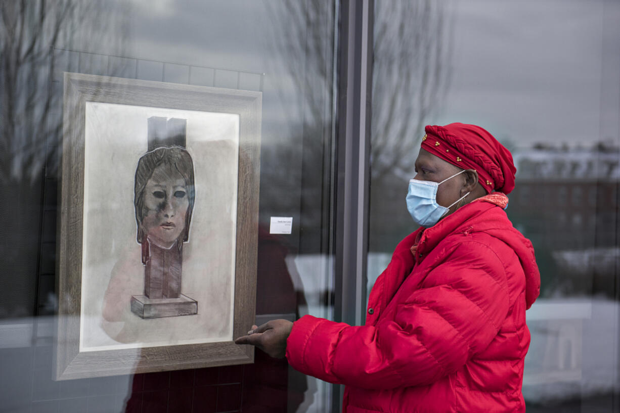 Artist Claudia Carter looks over a piece titled, &quot;Self Portrait,&quot; in the side window exhibit at Vancouver Community Library in Vancouver. Carter has been putting on a Black History Month installation for four years. In February 2020, she was diagnosed with cancer and her goal was to live until at least February 2021 for one last installation.