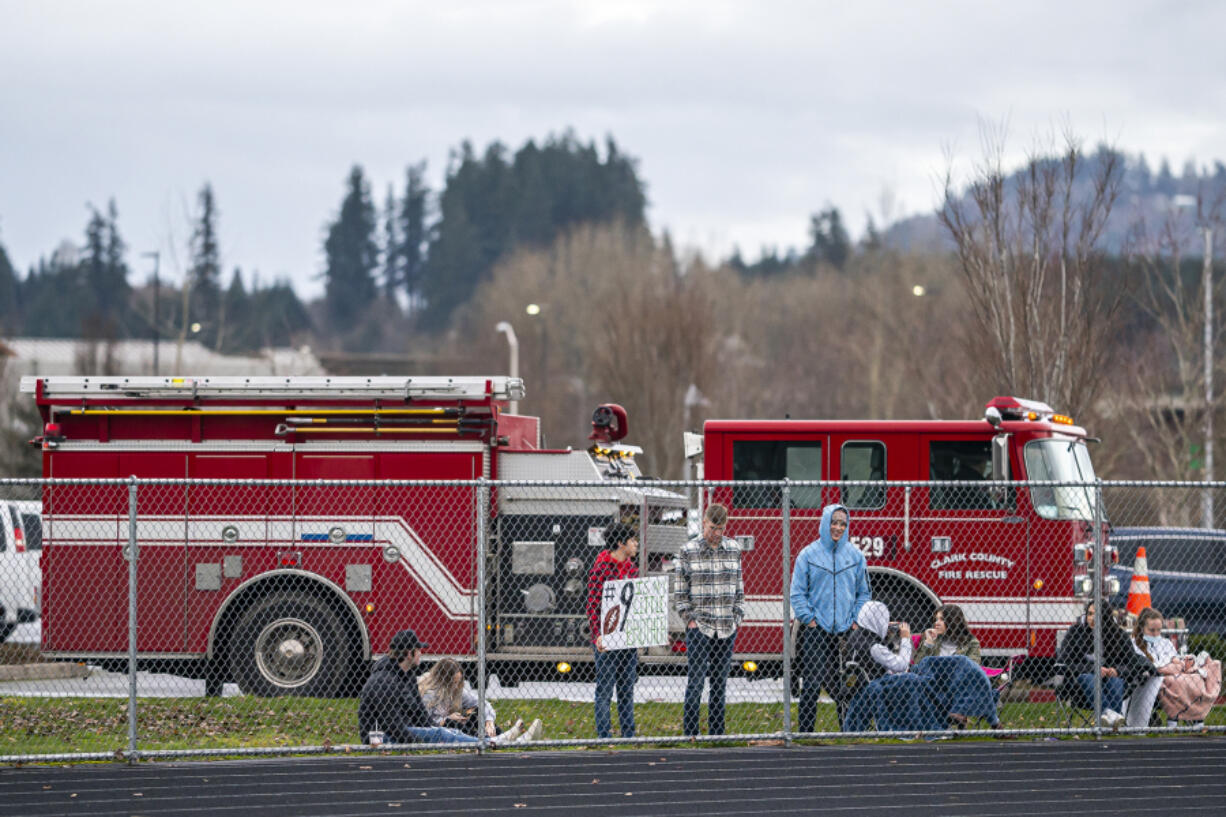 Fans watch from behind a perimeter fence during Saturday&#039;s game between Columbia River and Woodland. The game at Woodland High School was played with limited crowd capacity because of COVID-19 restrictions.