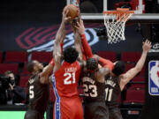 Philadelphia 76ers center Joel Embiid (21) goes after a rebound with Portland Trail Blazers guard Rodney Hood, left, forward Robert Covington, center, and center Enes Kanter, right, during the first half of an NBA basketball game in Portland, Ore., Thursday, Feb. 11, 2021.