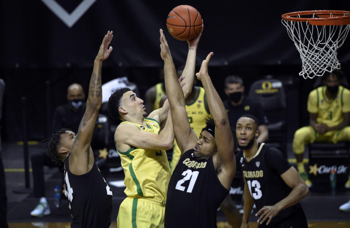 Oregon guard Chris Duarte (5) drives past Colorado guard Eli Parquet (24) and forward Evan Battey (21) as Colorado forward Dallas Walton (13) watches during the second half of an NCAA college basketball game Thursday, Feb. 18, 2021, in Eugene, Ore.