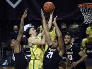 Oregon guard Chris Duarte (5) drives past Colorado guard Eli Parquet (24) and forward Evan Battey (21) as Colorado forward Dallas Walton (13) watches during the second half of an NCAA college basketball game Thursday, Feb. 18, 2021, in Eugene, Ore.