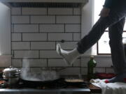 Jorge Sanhueza-Lyon stands on his kitchen counter to warm his feet over his gas stove Tuesday, Feb. 16, 2021, in Austin, Texas. Power was out for thousands of central Texas residents after temperatures dropped into the single digits when a snow storm hit the area on Sunday night.