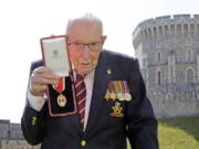 FILE - In this Friday, July 17, 2020 file photo, Captain Sir Thomas Moore poses for the media after receiving his knighthood from Britain&#039;s Queen Elizabeth, during a ceremony at Windsor Castle in Windsor, England. Tom Moore, the 100-year-old World War II veteran who captivated the British public in the early days of the coronavirus pandemic with his fundraising efforts, has died, Tuesday Feb. 2, 2021.