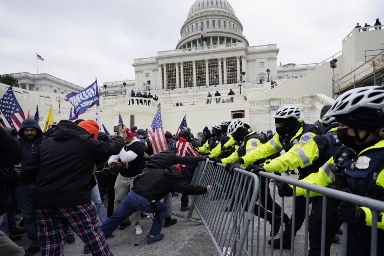 FILE - In this Jan. 6, 2021 file photo, rioters try to break through a police barrier at the Capitol in Washington.  People charged in the attack on the U.S. Capitol left behind a trove of videos and messages that have helped federal authorities build cases. In nearly half of the more than 200 federal cases stemming from the attack, authorities have cited evidence that an insurrectionist appeared to have been inspired by conspiracy theories or extremist ideologies, according to an Associated Press review of court records.