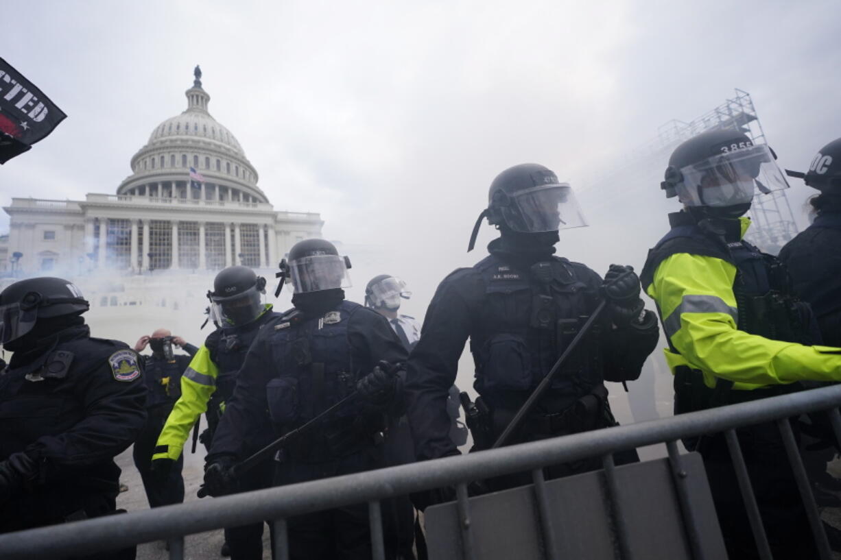 FILE - In this Jan. 6, 2021, file photo, police stand guard after holding off Trump supporters who tried to break through a police barrier at the Capitol in Washington. As federal officials grapple with how to confront the national security threat from domestic extremists after the deadly siege of the U.S. Capitol, civil rights groups and communities of color are watching warily for any moves to expand law enforcement power or authority.