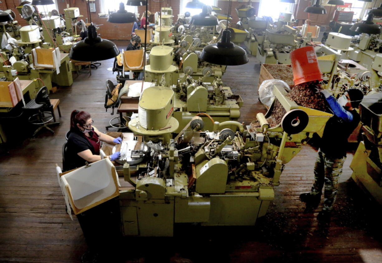 FILE - In this Dec. 14, 2020 file photo, Zeida Hernandez, of Tampa, Fla., left, makes Factory Throwout cigars using an antique hand-operated cigar machine at the J.C. Newman Cigar Co., Tampa&#039;s last cigar factory, in Fla. American factories grew in December at the fastest pace in more than two years as manufacturing continued to weather the pandemic better than the battered services sector. (Douglas R.