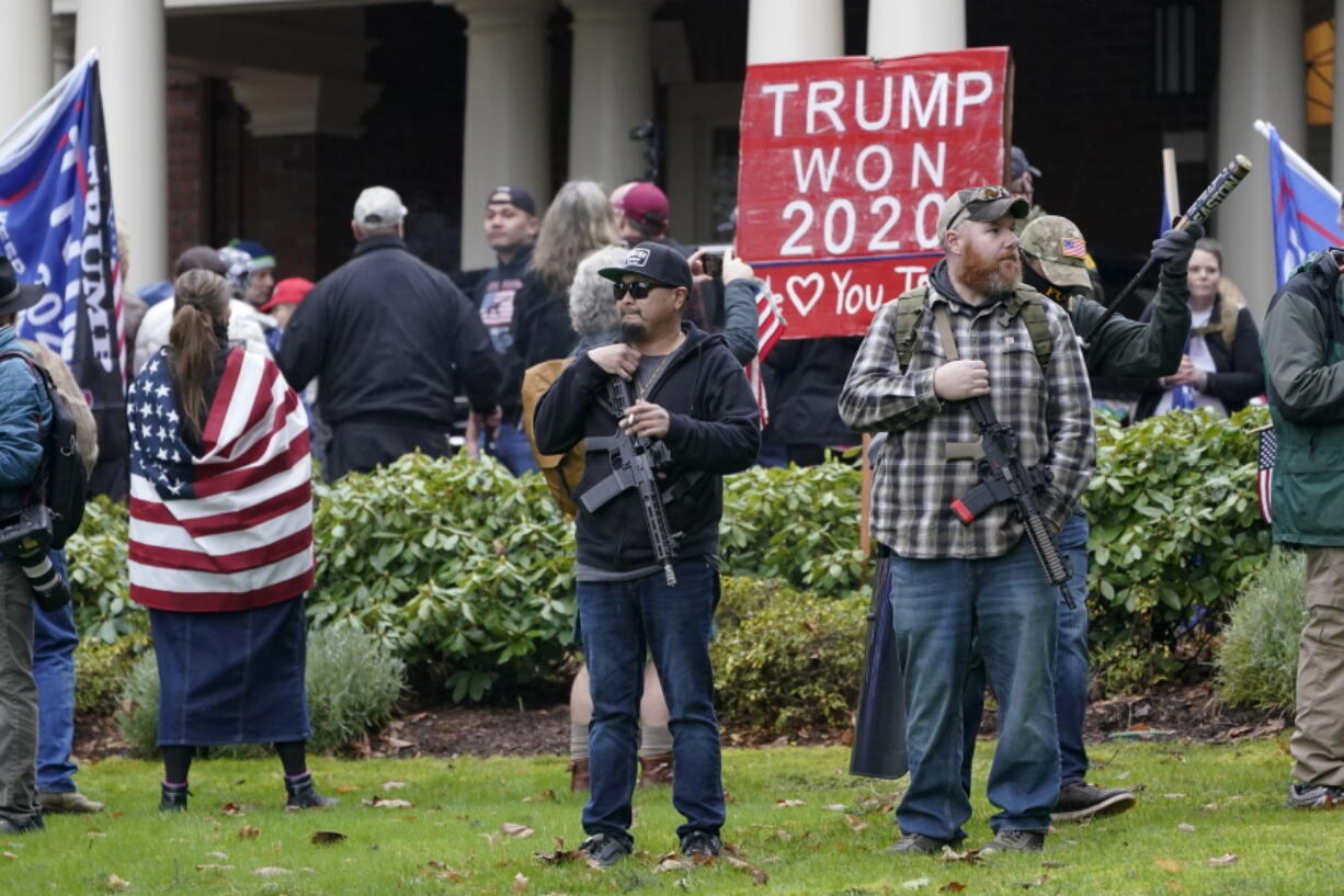 FILE - In this Jan. 6, 2021 file photo, two men stand armed with guns in front of the Governor&#039;s Mansion in Olympia, Wash., during a protest supporting President Donald Trump and against the counting of electoral votes in Washington, D.C., affirming President-elect Joe Biden&#039;s victory.  (AP Photo/Ted S.