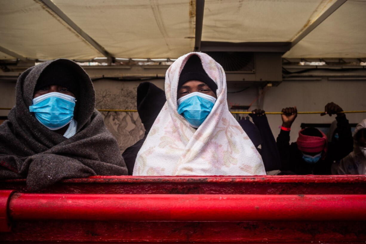 Migrants stand on the deck of the Ocean Viking rescue ship, in the Mediterranean Sea on Sunday, Feb. 7, 2021. A rescue ship with 422 migrants aboard, some of whom tested positive for COVID-19, is heading to Sicily. SOS Mediterranee, the humanitarian group which operates the rescue ship Ocean Viking, told The AP on Sunday that Italy granted the vessel permission to enter the port of Augusta.