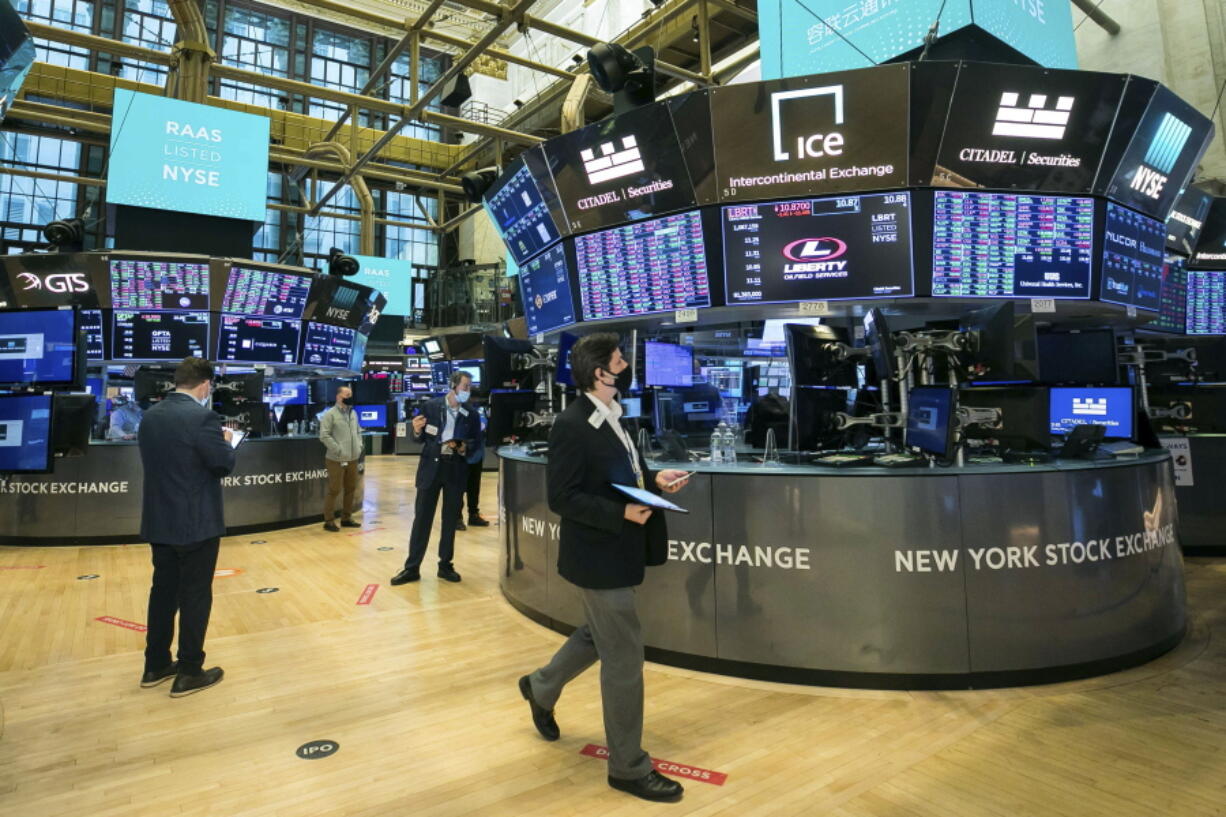 In this photo provided by the New York Stock Exchange, traders work on the floor, Tuesday, Feb. 9, 2021. Stocks were slightly lower in early trading on Tuesday, after the major stock market indexes hit record highs the day before. Investors continue to keep their eyes on Washington, where it appears Democrats plan to move ahead without Republican help on a major stimulus bill for the economy.