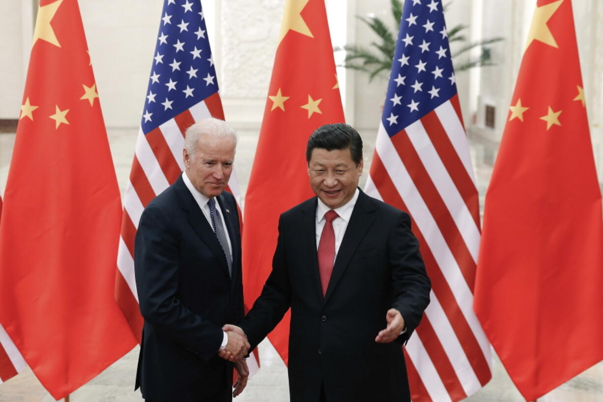 FILE - In this Dec. 4, 2013, file photo, Chinese President Xi Jinping, right, shakes hands with then U.S. Vice President Joe Biden as they pose for photos at the Great Hall of the People in Beijing.