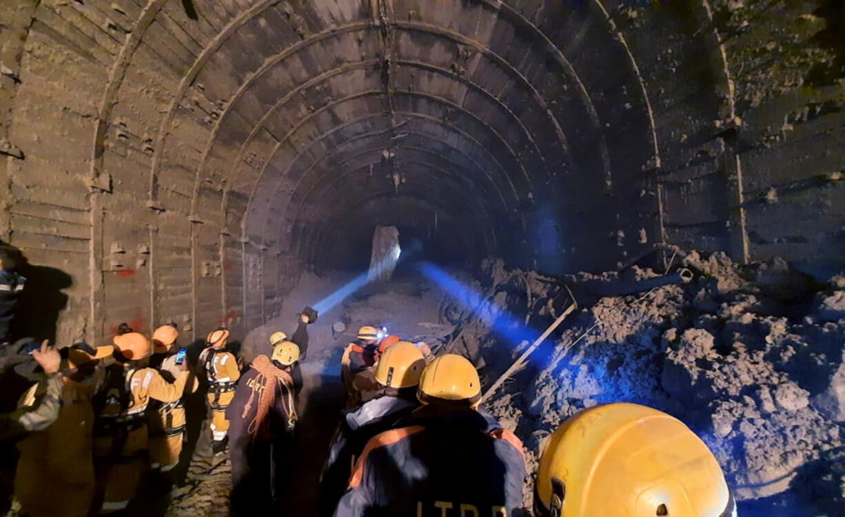 This photograph provided by Indo Tibetan Border Police (ITBP) shows ITBP personnel use torches to gain access inside a tunnel to rescue more than three dozen power plant workers trapped inside Tuesday in the Tapovan area of the northern state of Uttarakhand, India.