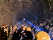 This photograph provided by Indo Tibetan Border Police (ITBP) shows ITBP personnel use torches to gain access inside a tunnel to rescue more than three dozen power plant workers trapped inside Tuesday in the Tapovan area of the northern state of Uttarakhand, India.