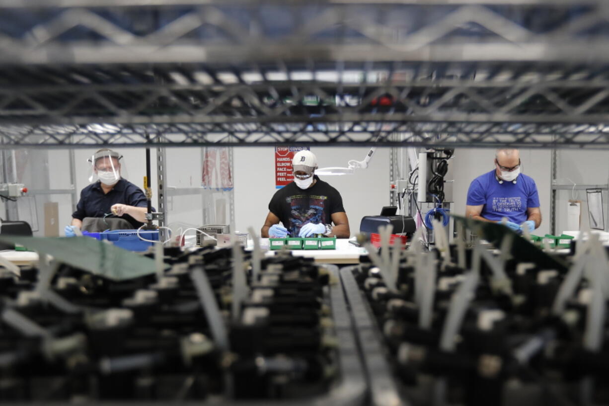 FILE - In this May 13, 2020, file photo, Ford Motor Co., line workers put together ventilators that the automaker is assembling at the Ford Rawsonville plant in Ypsilanti Township, Mich. U.S. industrial production increased 0.4% in November with manufacturing receiving a boost from a rebound in output at auto plants after three months of declines. The Federal Reserve reported Tuesday, Dec. 15 that the November gain in industrial output followed an even stronger 0.9% increase in October.