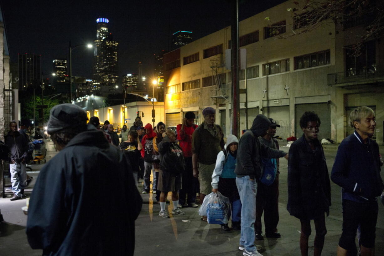 FILE - In this Sept. 19, 2017, file photo, people line up for free food being given out in an area of downtown Los Angeles known as Skid Row. A fed up federal judge says a rain storm during the last week of January 2021 created &quot;extraordinarily harsh&quot; conditions for homeless residents of Los Angeles and he has ordered city officials to meet with him at a Skid Row shelter to discuss how to address the worsening crisis of people living on the streets. (AP Photo/Jae C.