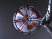 This image from video shows the parachute deployed during the descent of the Mars Perseverance rover Thursday. Systems engineer Ian Clark used a binary code to spell out &quot;Dare Mighty Things&quot; in the orange and white strips of the 70-foot parachute.