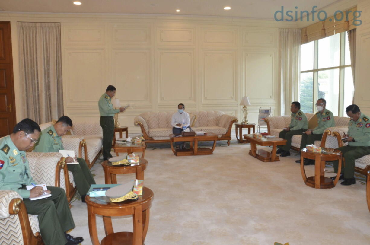 In this photo released by The Military True News Information Team, Myanmar Acting President Myint Swe, center, military chief Senior Gen. Min Aung Hlaing, standing at left, and other military members of National Defence and Security Council attend a meeting at Presidential Palace in Naypyitaw, Myanmar Monday, Feb. 1, 2021.