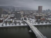 An aerial view of the Morrison Bridge and downtown Portland, Ore., is seen during a snowstorm, on Friday, Feb. 12, 2021. A winter storm has blanketed the Pacific Northwest with ice and snow, leaving hundreds of thousands of people without power and disrupting travel across the region.