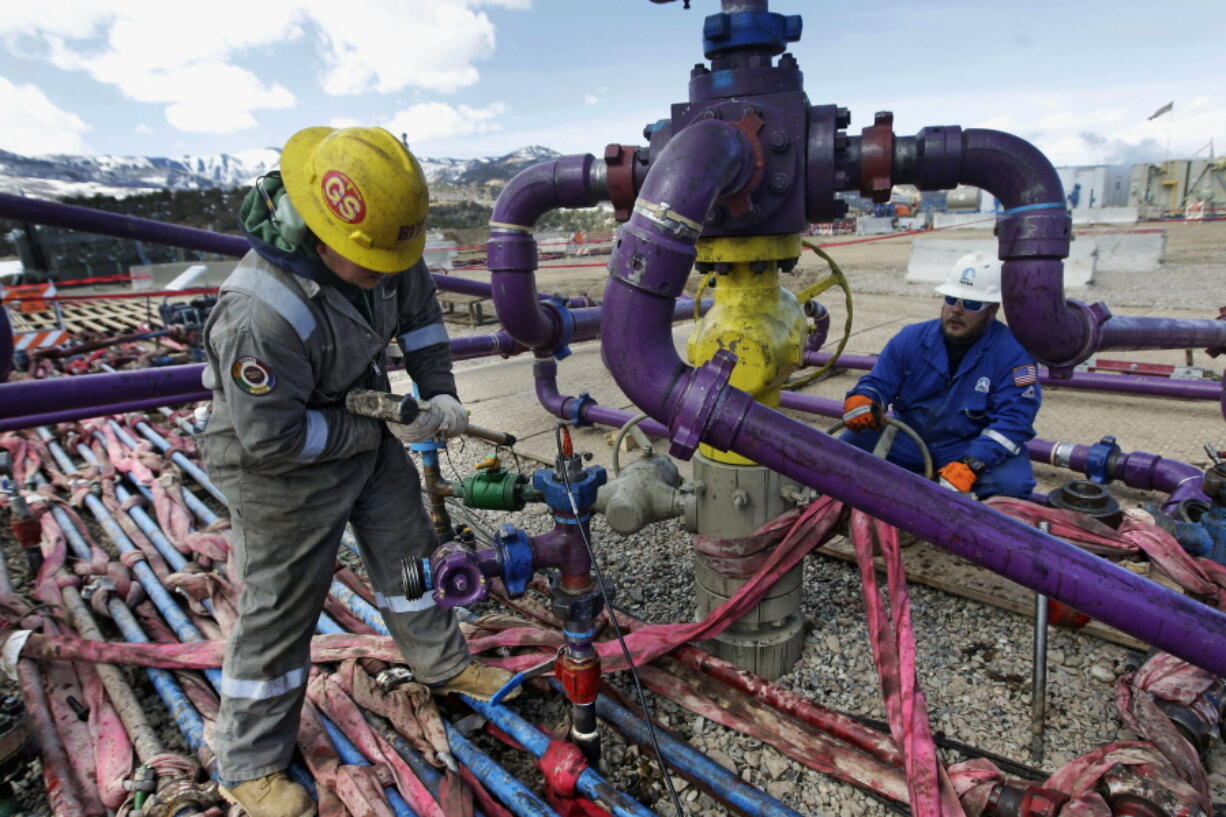 FILE - In this March 29, 2013, file photo, workers tend to a well head during a hydraulic fracturing operation outside Rifle, in western Colorado. The Interior Department said Friday, Feb. 12, 2021 that it is postponing onshore and offshore oil lease sales planned for next month in line with President Joe Biden&#039;s executive order on climate change.