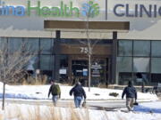 FILE - In this Tuesday, Feb. 9, 2021 file photo, law enforcement personnel walk toward the Allina Health clinic where multiple people were shot in Buffalo, Minn. Doctors say they&#039;re facing increasing threats of violence for refusing to prescribe opioids or trying to wean patients off the addictive painkillers. The issue was underscored by Tuesday&#039;s shooting at the Minnesota clinic.