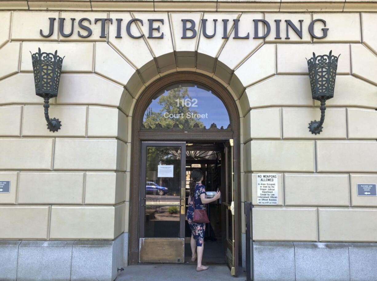 FILE - In this May 28, 2020 file photo a woman enters the Oregon Department of Justice building in Salem, Ore. The Oregon Supreme Court, ruling in a murder case, has upheld that a defendant may be acquitted by a nonunanimous verdict. This comes months after the U.S. Supreme Court ruled that guilty verdicts must be unanimous. Oregon is the only state that allows split jury verdicts -- but only for not guilty verdicts.