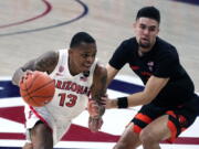 Arizona guard James Akinjo (13) drives by Oregon State guard Jarod Lucas during the first half of an NCAA college basketball game, Thursday, Feb. 11, 2021, in Tucson, Ariz.