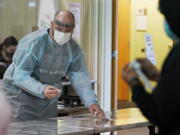 Brant McAdams, left, football coach at Pacific Lutheran, wears personal protective equipment as he prepares COVID-19 tests for student athletes Wednesday, Feb. 3, 2021, on campus in Tacoma, Wash. There was never a chapter in any of the books on becoming a small NCAA college football coach that addressed administering COVID-19 tests in the midst of a pandemic, but now it&#039;s something he&#039;s doing to give his players the chance at a season. (AP Photo/Ted S.