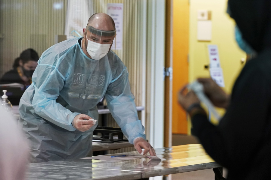 Brant McAdams, left, football coach at Pacific Lutheran, wears personal protective equipment as he prepares COVID-19 tests for student athletes Wednesday, Feb. 3, 2021, on campus in Tacoma, Wash. There was never a chapter in any of the books on becoming a small NCAA college football coach that addressed administering COVID-19 tests in the midst of a pandemic, but now it&#039;s something he&#039;s doing to give his players the chance at a season. (AP Photo/Ted S.