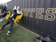 Pacific Lutheran players take part in a blocking drill against a storage container during football practice Tuesday in Tacoma. For all the attention heaped on the FBS level of college football last fall as it tried to play, it will not be the only college football during the 2020-21 sports calendar as a handful of NCAA Division III and NAIA programs begin some form of a winter/spring season Saturday. (Photos by Ted S.