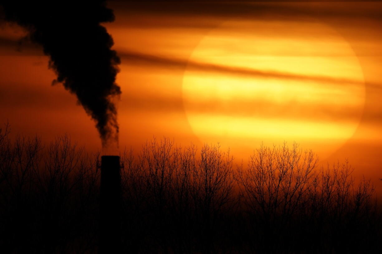 Emissions from a coal-fired power plant are silhouetted against the setting sun, Monday, Feb. 1, 2021, in Independence, Mo. A United Nations report released on Thursday, Feb. 18, 2021 says humans are making Earth a broken and increasingly unlivable planet through climate change, biodiversity loss and pollution. So the world must make dramatic changes to society, economics and daily life.