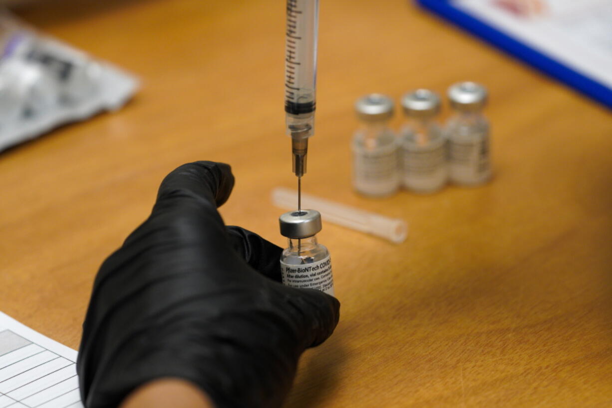 FILE - In this Feb. 12, 2021, file photo, scripps health official draws from a vile of the COVID-19 vaccine prior to administering it at their new drive-thru vaccination site at the Del Mar Fairgrounds in Del Mar, Calif. Executives from the major COVID-19 vaccine producers are set Tuesday, Feb. 23, to answer questions from Congress about expanding the supply of shots needed to curb the pandemic that has killed more than 500,000 Americans. (Nelvin C.