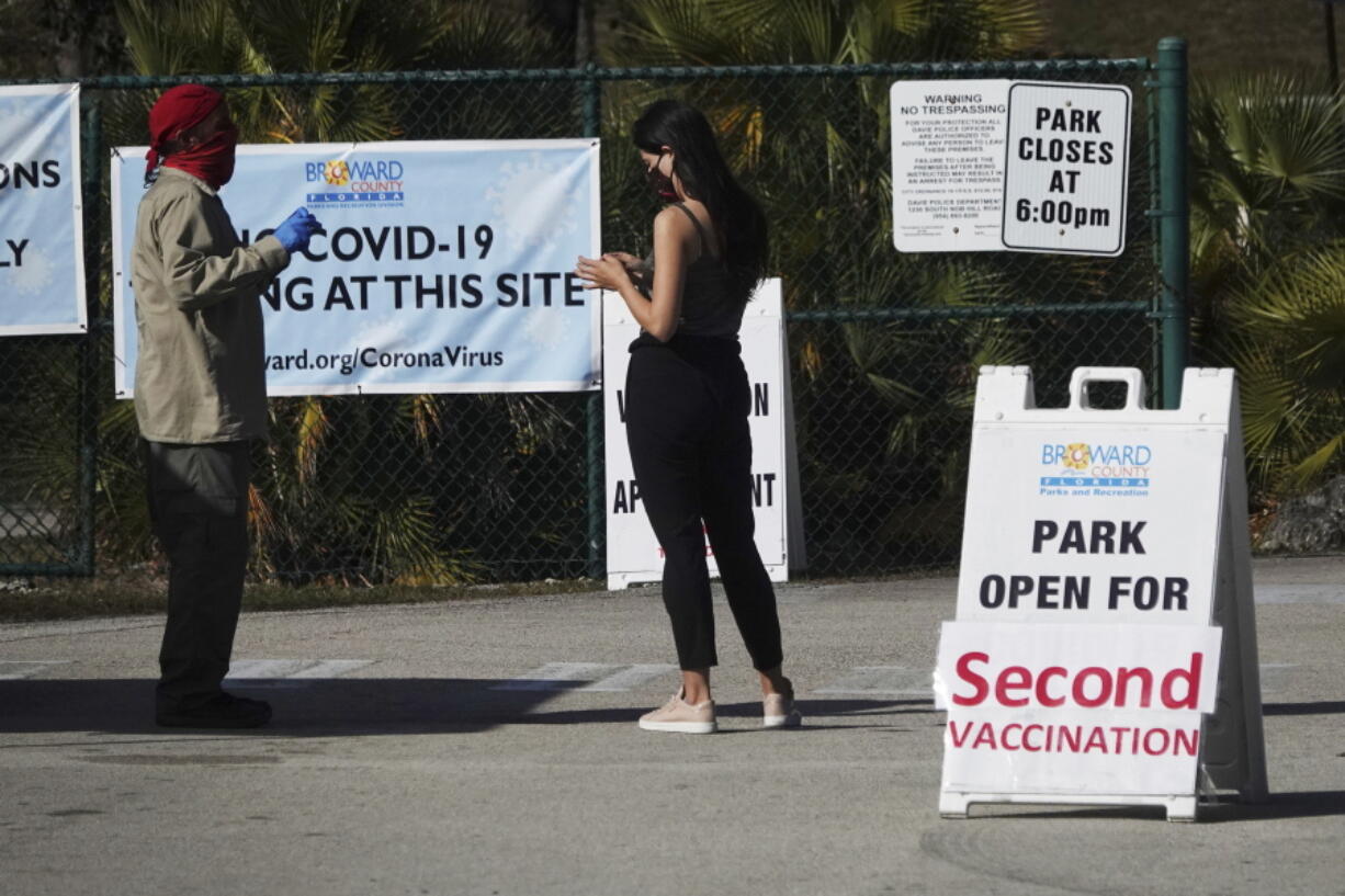 FILE - In this Jan. 27, 2021, file photo, woman asks directions at the entrance to Vista View Park where a COVID-19 vaccination site has opened for second doses in Davie, Fla. As health officials race to vaccinate people across the U.S., the need to give each person two doses a few weeks apart is adding a layer of complexity to the country&#039;s biggest-ever vaccination campaign.