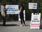 FILE - In this Jan. 27, 2021, file photo, woman asks directions at the entrance to Vista View Park where a COVID-19 vaccination site has opened for second doses in Davie, Fla. As health officials race to vaccinate people across the U.S., the need to give each person two doses a few weeks apart is adding a layer of complexity to the country&#039;s biggest-ever vaccination campaign.