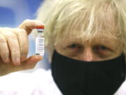 FILE - In this Wednesday, Feb. 17, 2021 file photo, Britain&#039;s Prime Minister Boris Johnson holds a vial of the Oxford/Astra Zeneca Covid-19 vaccine at a vaccination centre in Cwmbran, south Wales. The British government says it aims to give every adult in the country a first dose of coronavirus vaccine by July 31, a month earlier than its previous target. In addition, the goal is for everyone over 50 or with an underlying health condition to get a shot by April 15, rather than the previous target of May 1.