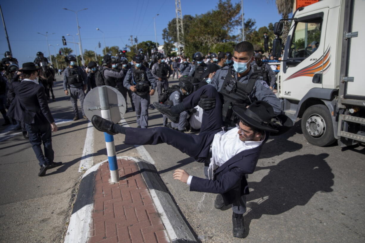 File - In this Sunday, Jan. 24, 2021 file photo, Israeli police officers clash with ultra-Orthodox Jews in Ashdod, Israel,. Ultra-Orthodox demonstrators clashed with Israeli police officers dispatched to close schools in Jerusalem and Ashdod that had opened in violation of coronavirus lockdown rules, on Sunday.