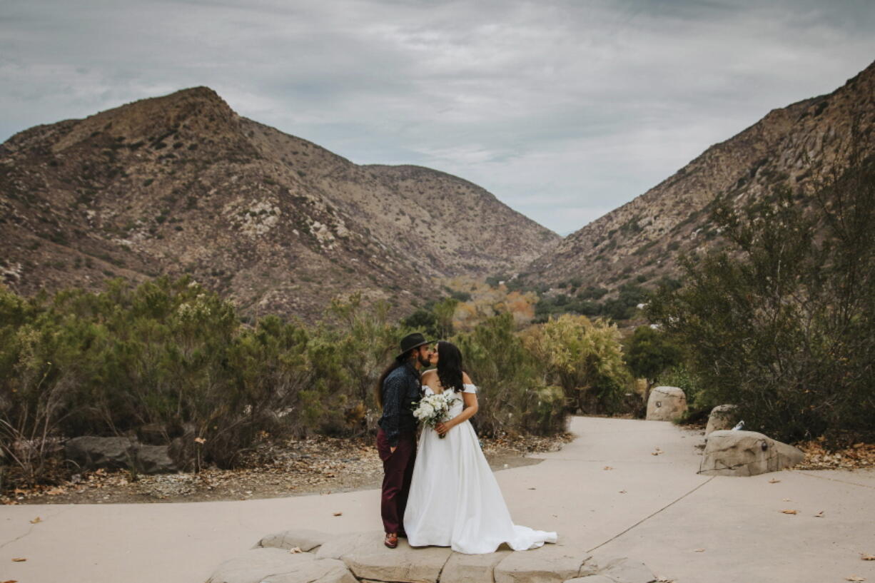 In this Sunday, Dec. 27, 2020 photo provided by Kristen Pritchard Photography, Kayleigh and Cody Cousins pose for wedding photos at Mission Trails Regional Park in San Diego, Calif. They initially planned an April 2020 wedding, postponed it after the pandemic took hold, rescheduled it for December, then had to shift gears again when a new lockdown was imposed. &quot;That was devastating,&quot; said Kayleigh.