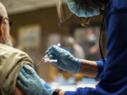 FILE- In this Feb. 2, 2021 file photo, Tyson Foods team members receive Covid-19 vaccines from health officials at the Wilkesboro, N.C. facility. Hundreds of meatpacking workers have been vaccinated against the coronavirus but the union that represents them says several hundred thousand more have not, despite the risks they continue to face at work.