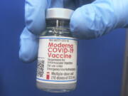 A vial of Moderna COVID-19 vaccine is held at a vaccination site Friday, Feb. 19, 2021, in Oklahoma City.