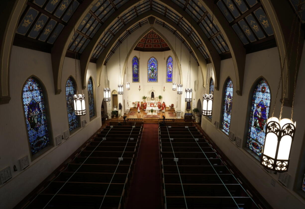 FILE - In this Sunday, April 5, 2020, file photo, The Most Rev. Peter Jugis, Bishop of Charlotte, conducts Palm Sunday services inside the empty St. Patrick Cathedral in Charlotte, N.C. Due to the coronavirus pandemic, the service was closed to the public but was live streamed across western North Carolina. Catholic entities in the Charlotte Diocese received more than $8 million in paycheck program aid. (David T.