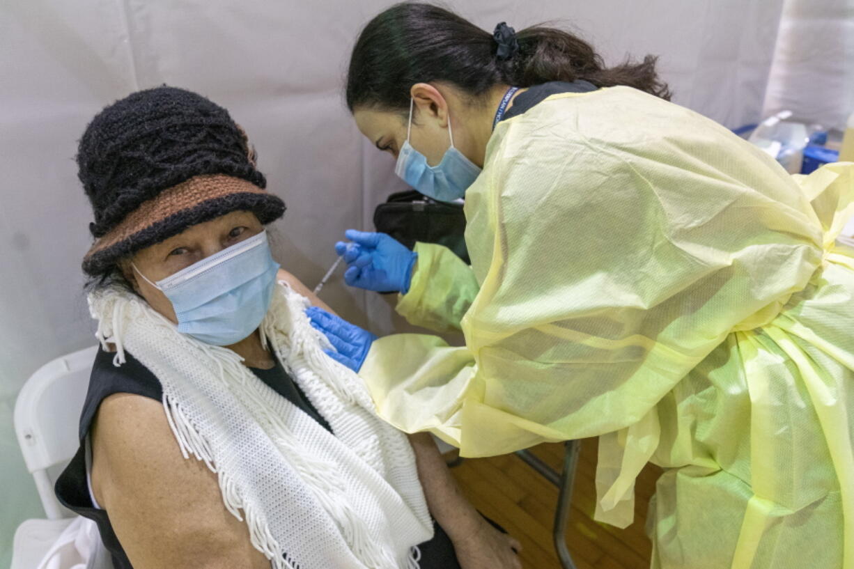 FILE - In this Jan. 31, 2021, file photo, registered Nurse Rita Alba gives a patient the first dose of the coronavirus vaccine at a pop-up COVID-19 vaccination site at the Bronx River Community Center in the Bronx borough of New York. The deadliest month of the coronavirus outbreak in the U.S. drew to a close with certain signs of progress: COVID-19 cases and hospitalizations are trending downward, while vaccinations are picking up speed.